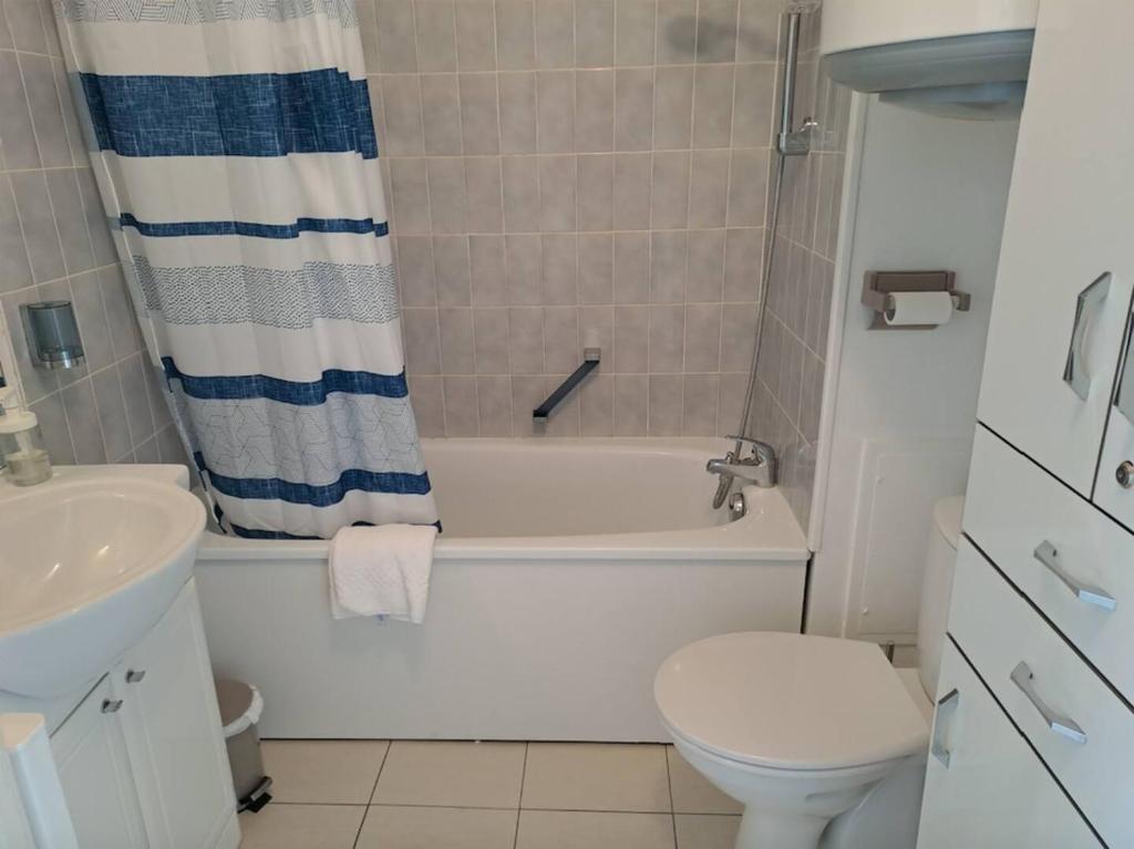 une salle de bain avec une baignoire, des toilettes et un lavabo dans l'établissement L'Evasion, F2 proche mer et commerce, parking & wifi, à Villers-sur-Mer