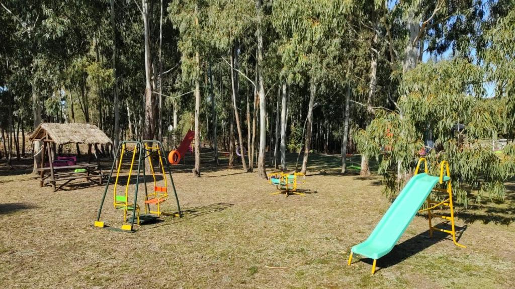 a playground with three swings and a slide at Cabañas MyG in Tandil