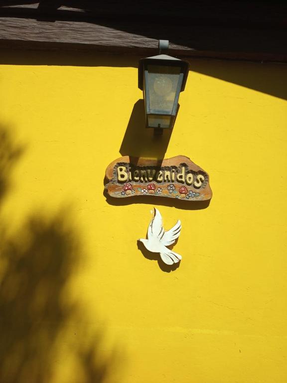 a sign on the side of a yellow building with a bird at Chalet Paloma 3 in La Falda