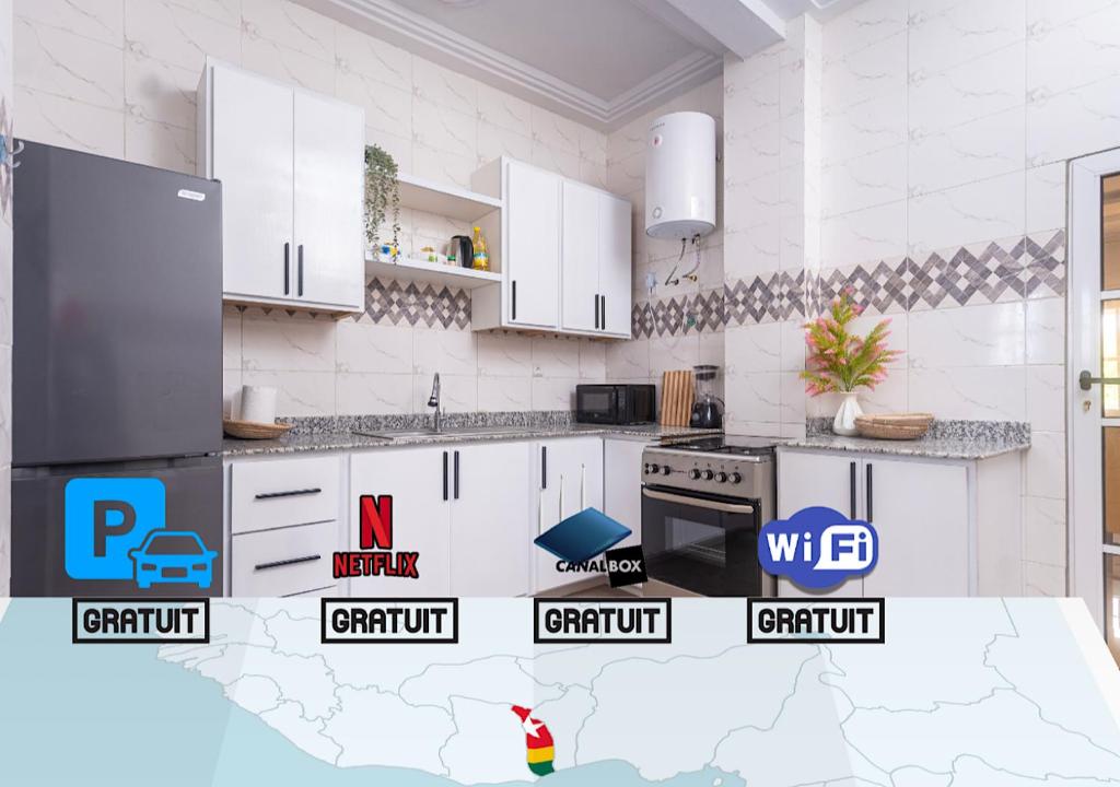 una cocina con armarios blancos y logotipos en las encimeras en magnifique appartement, de deux balcons, très spacieux, en Baguida