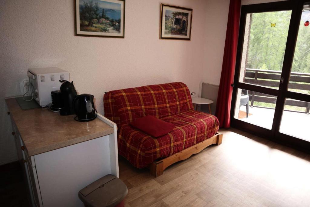 un salon avec une chaise rouge et une table dans l'établissement Résidence Les Flocons - Résidence Les Flocons MAE-6164, aux Orres