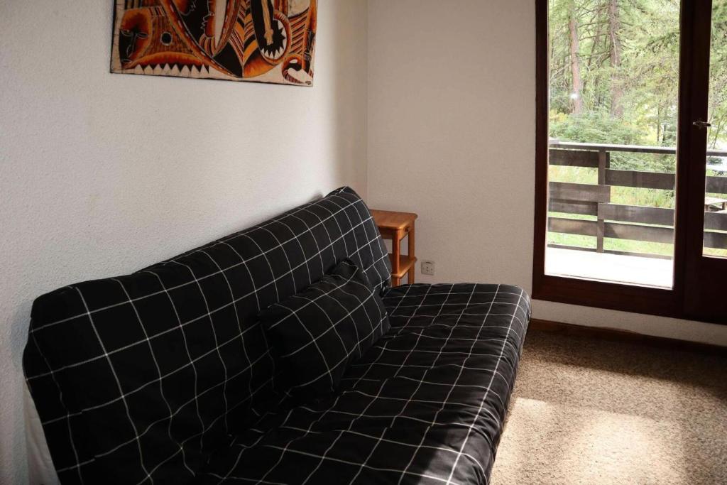 un canapé noir dans un salon avec une fenêtre dans l'établissement Résidence Le Pouzenc - Studio calme pieds de pistes MAE-6471, aux Orres