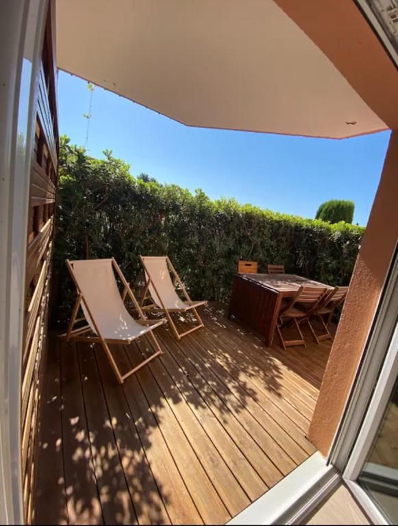 deux chaises et une table sur une terrasse en bois dans l'établissement A 15 min de la plage, piscine, joli T2 Rénové, à Fréjus