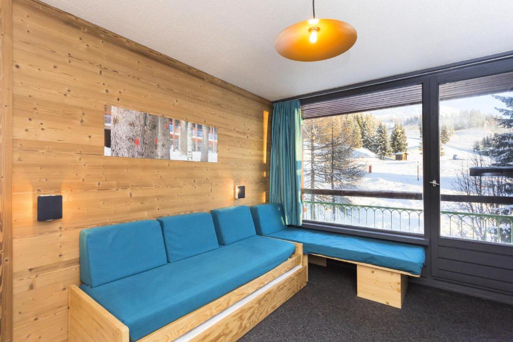 une chambre avec un canapé bleu et une fenêtre dans l'établissement Résidence Lauzieres - Studio 5 personnes pied des pistes MAE-5084, à Arc 1800