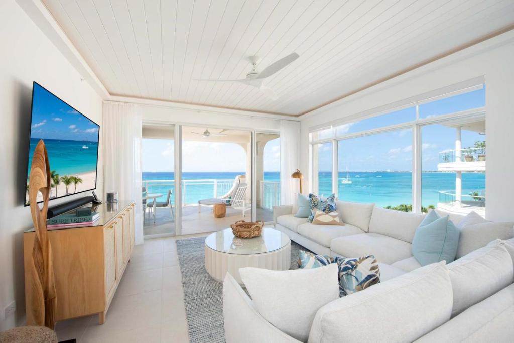 a living room with white furniture and a view of the ocean at Beachcomber 35 in George Town