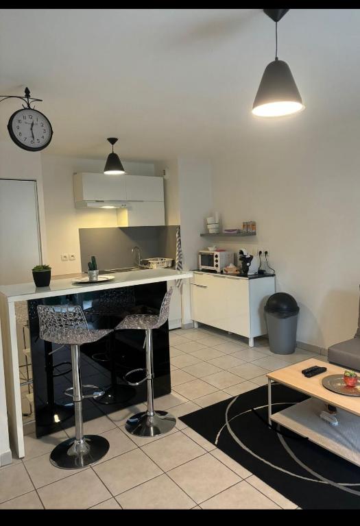 une cuisine avec un comptoir et deux tabourets de bar dans l'établissement T2 cosy tout équipé à deux pas de la gare de annemasse, à Ville-la-Grand
