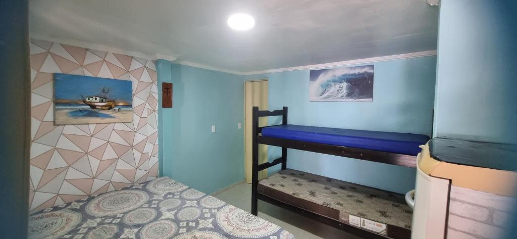 a small bedroom with a bunk bed with blue walls at Hospedagem da Família hostel in Cabo Frio