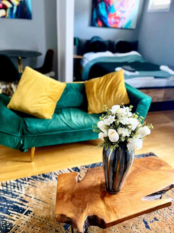 a living room with a green couch and a vase with flowers at Apartment-City in Cologne