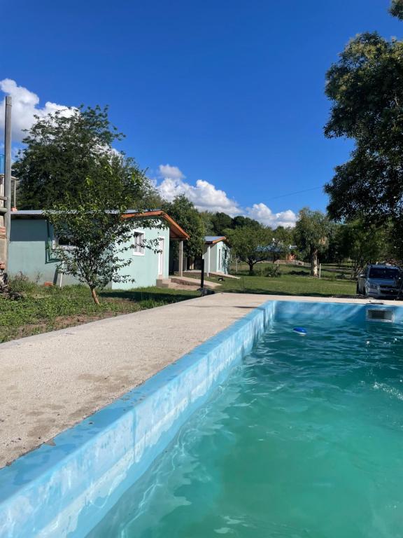 una piscina con agua azul frente a una casa en Cabañas D Noris, en Los Hornillos