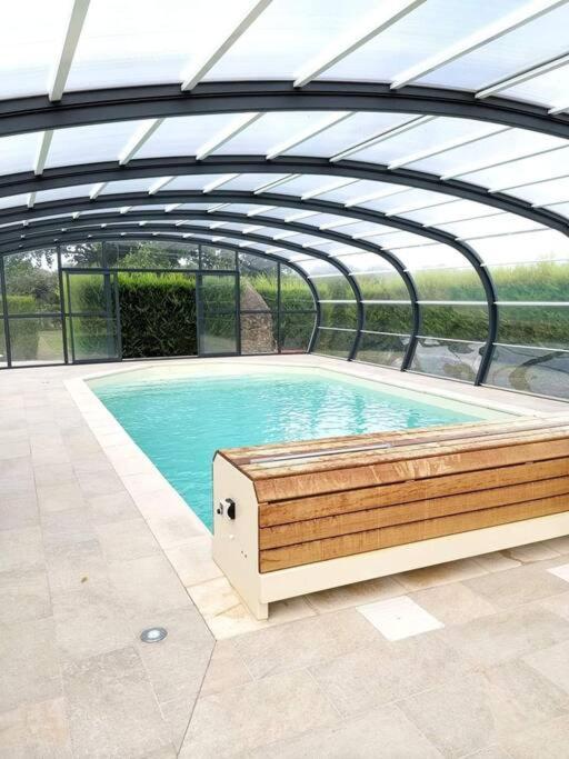 - une piscine avec un banc en bois dans un bâtiment dans l'établissement À la campagne proche du Mans, à Louplande
