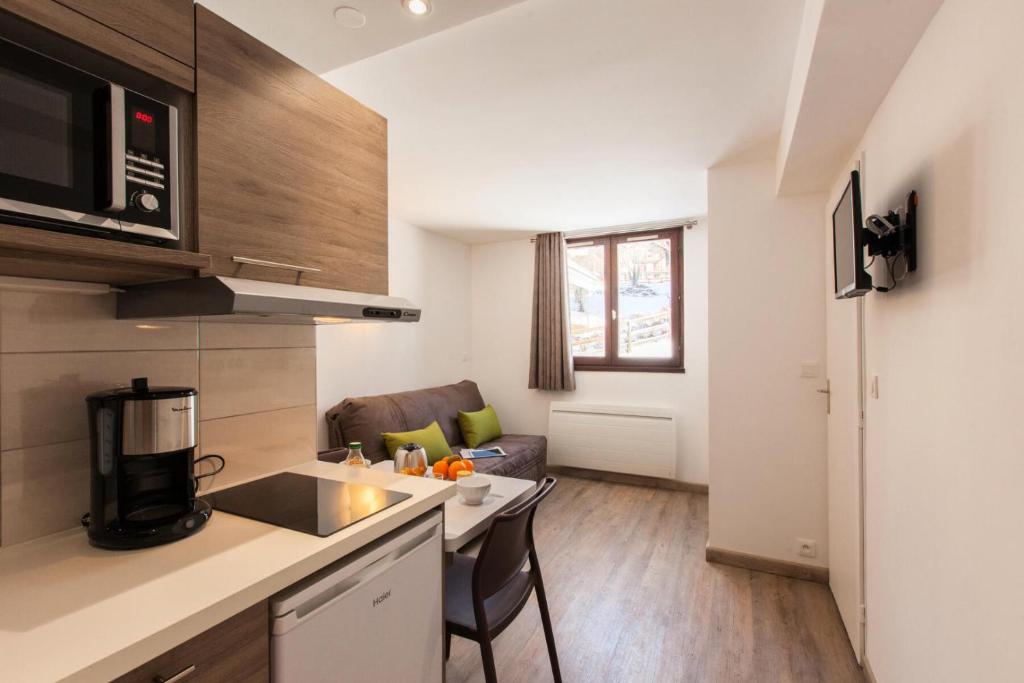 Il comprend une cuisine et un salon avec un comptoir et un four micro-ondes. dans l'établissement Résidence Bois Des Coqs - Studio rénové avec casier à skis · Cœur de station · Parking extérieur MAE-0264, à Champcella