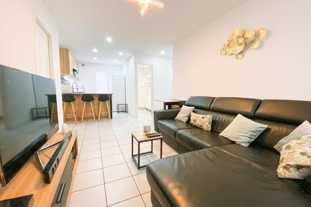 Il comprend un salon avec un canapé en cuir noir et une cuisine. dans l'établissement Le Vallier-Libération - Très bien situé, à Grenoble