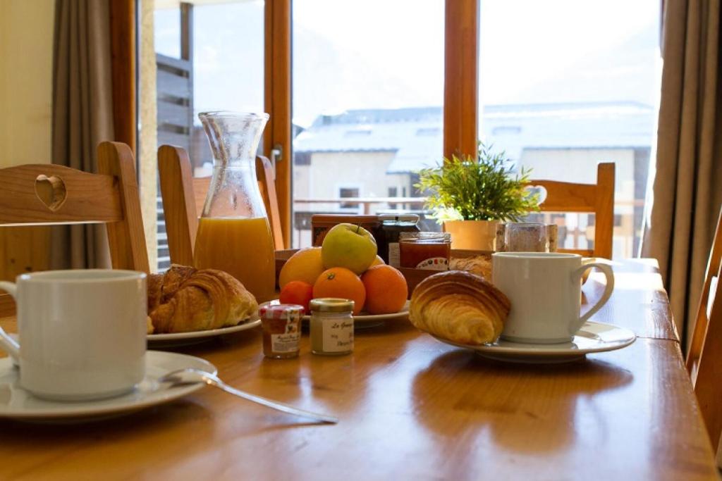 une table avec des assiettes de nourriture et deux tasses de café dans l'établissement Résidence Signal Du Prorel - Appartement rénové · Au pied des pistes · Wifi gratuit · Balcon et casier à skis MAE-0484, à Briançon