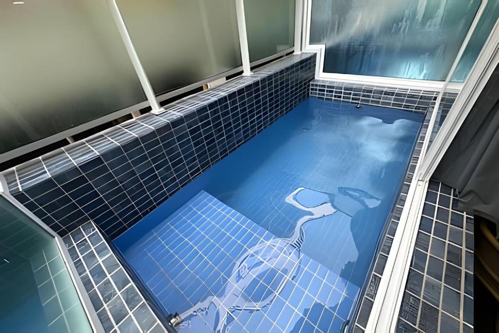 a swimming pool with a blue tiled floor at Flat Piscina Privativa 90 MT Praia centro in Porto De Galinhas