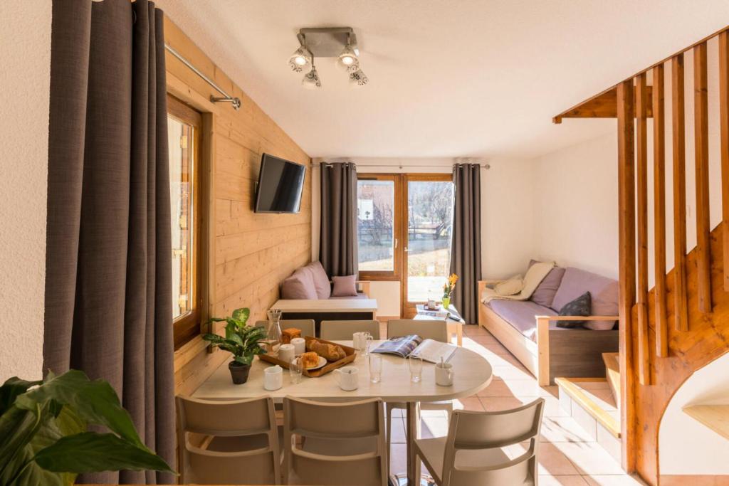 un salon avec une table et des chaises dans l'établissement Chalets Jardin Alpin - Chalet mitoyen duplex rénové · Accès pistes par navette · Terrasse · WIFI gratuit · Vue dégagée MAE-4824, à La Salle Les Alpes