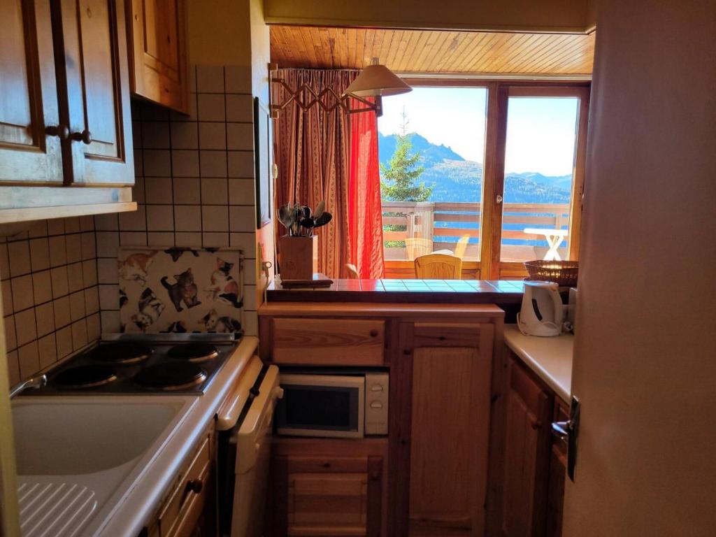 Il comprend une cuisine équipée d'une cuisinière. four supérieur à côté d'une fenêtre dans l'établissement Résidence Les Chavonnes - Appartement 2 pièces de 43m² pour 5/6 personnes MAE-7824, à Montvalezan