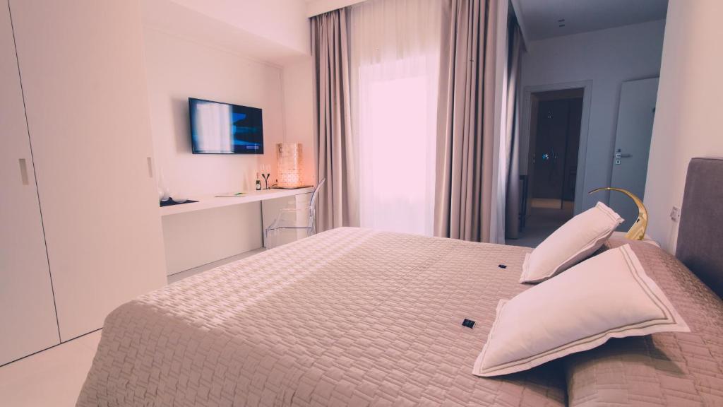 a white bedroom with a bed with two pillows at Siracusa Luxury Apartment in Reggio Calabria