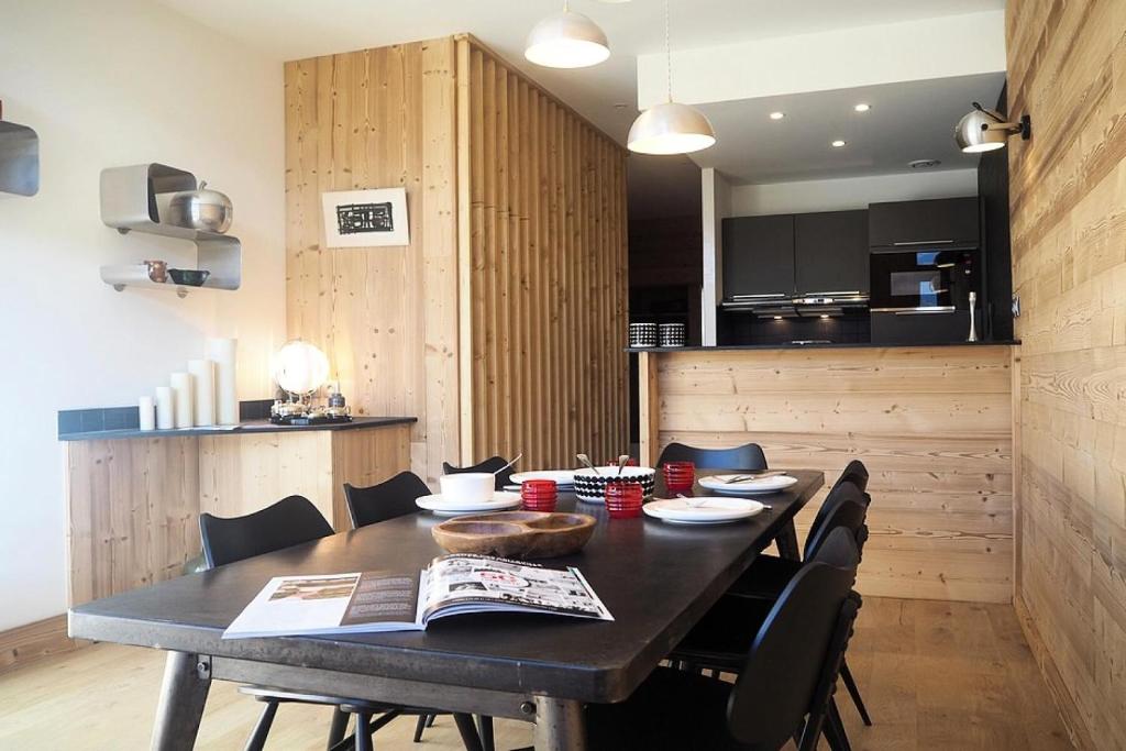 une table de salle à manger avec des chaises et une cuisine dans l'établissement Résidence Grande Masse - DUPLEX 4 pièces Rénové 8 personnes MAE-0094, aux Menuires