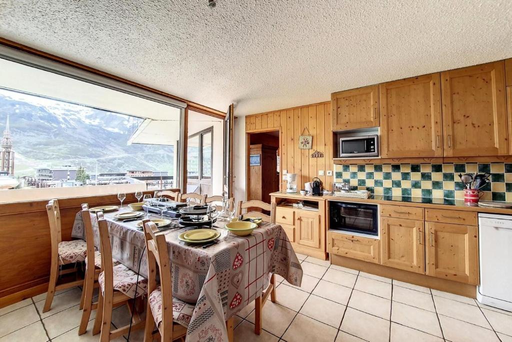 une cuisine avec une table et des chaises ainsi qu'une fenêtre dans l'établissement Résidence Aravis - Appartement spacieux · Skis aux pieds · Balcon vue station MAE-0244, aux Menuires