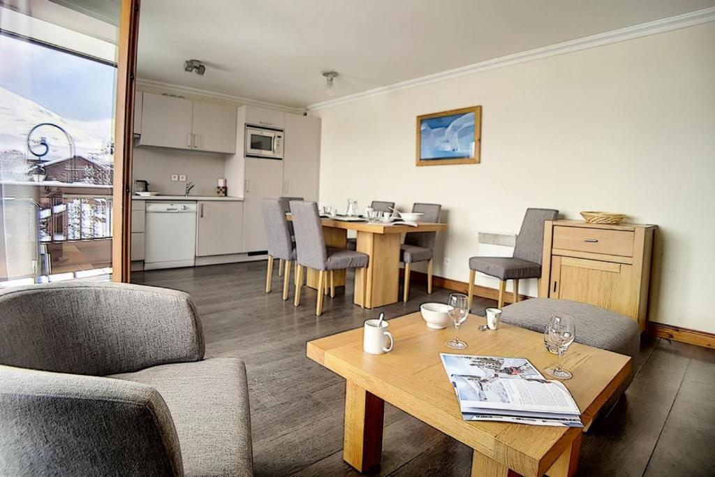 ein Wohnzimmer mit Tisch und Stühlen und eine Küche in der Unterkunft Résidence Les Cristaux - Appartement confortable et rénové · Proche des pistes · Balcon · Sauna · Hammam · WIFI MAE-0674 in Levassaix