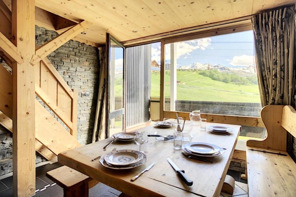 Cette chambre dispose d'une table en bois et d'une grande fenêtre. dans l'établissement Résidence Caron - Appartement duplex rénové · Départ ski aux pieds · Balcon MAE-0694, aux Menuires