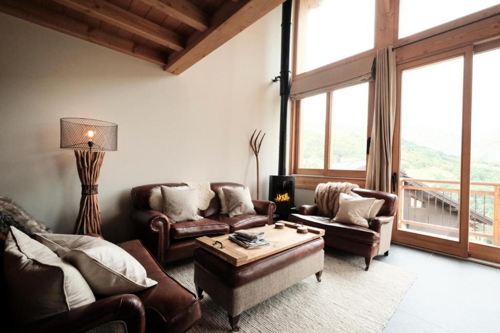 Elle comprend un salon doté d'un mobilier en cuir et d'une grande fenêtre. dans l'établissement Résidence Caseblanche - Chalet Carcosa MAE-0814, à Saint-Martin-de-Belleville