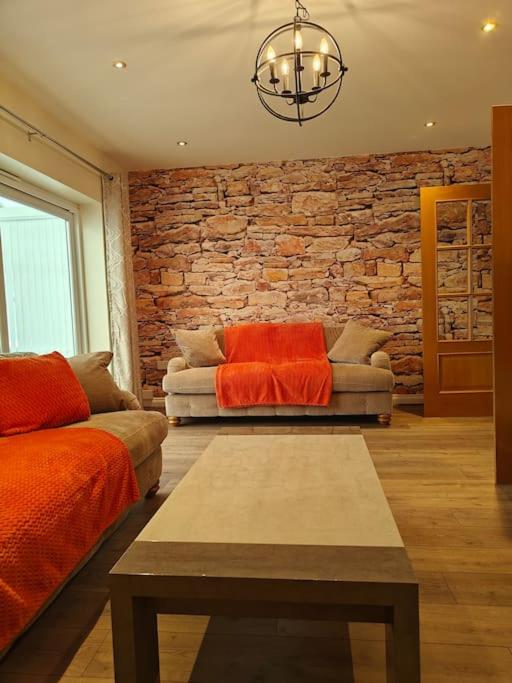 a living room with a couch and a brick wall at Stunning 5-bed House near NEC & BHX in Solihull