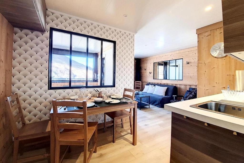 une cuisine et un salon avec une table et des chaises dans l'établissement Résidence Campanules - 2 pièces équipé pour 4 personnes MAE-1604, aux Menuires