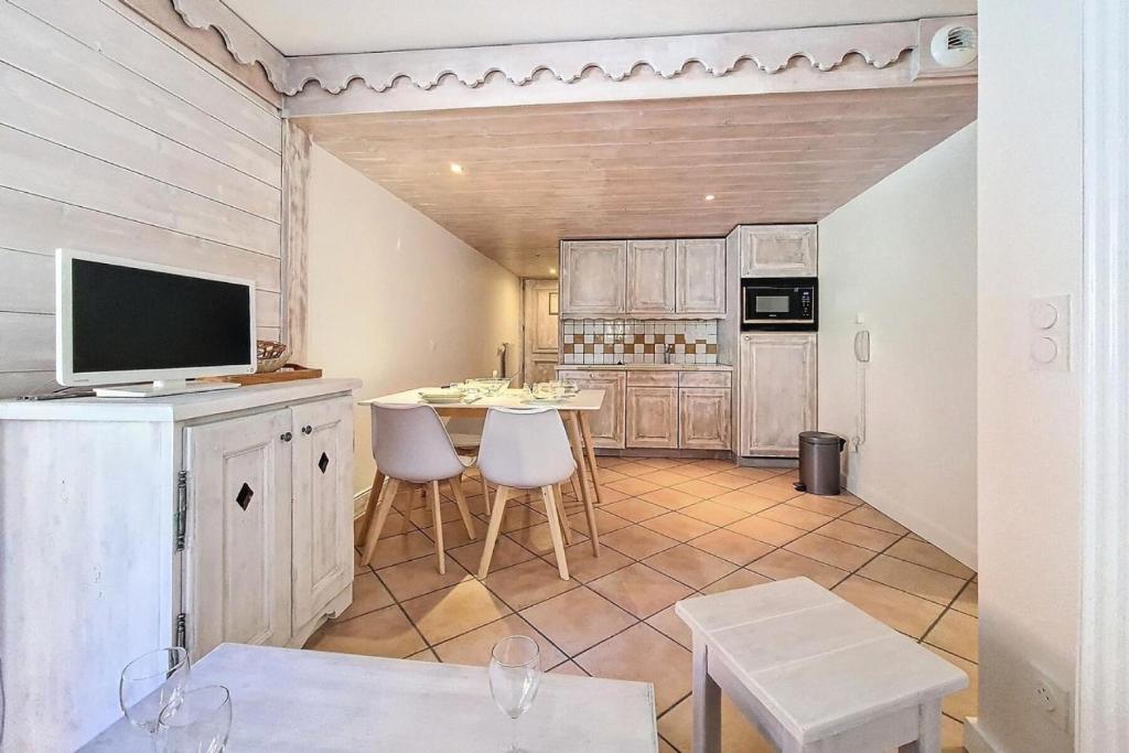 une cuisine avec une télévision et une table avec des chaises dans l'établissement Résidence Alpages De Reberty - Appartement rénové et lumineux· Proche des pistes · Balcon · Piscine MAE-1674, aux Menuires