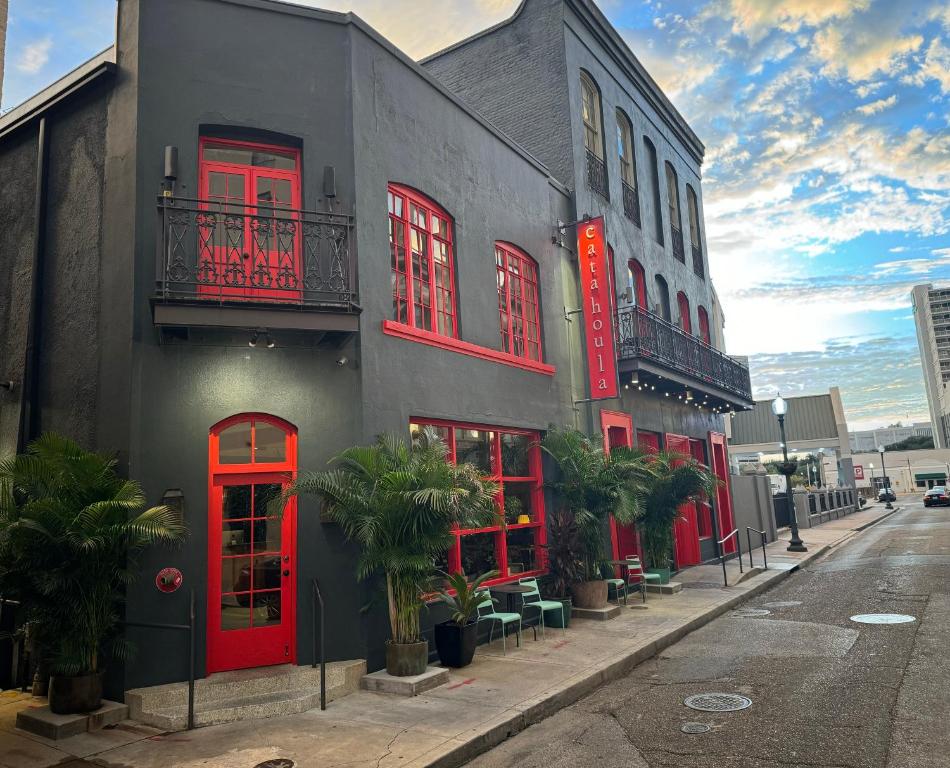 a building with red doors and windows on a street at Catahoula Hotel New Orleans in New Orleans