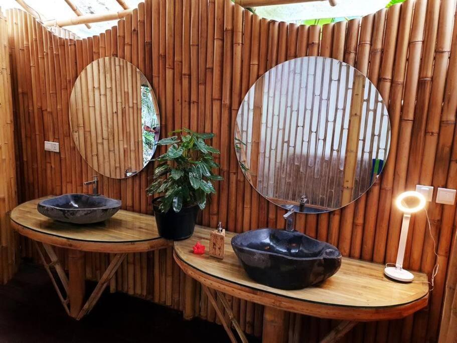 zwei Waschbecken im Bad mit zwei Spiegeln in der Unterkunft Eco Bamboo Island Bali - Bamboo House #1 in Selat