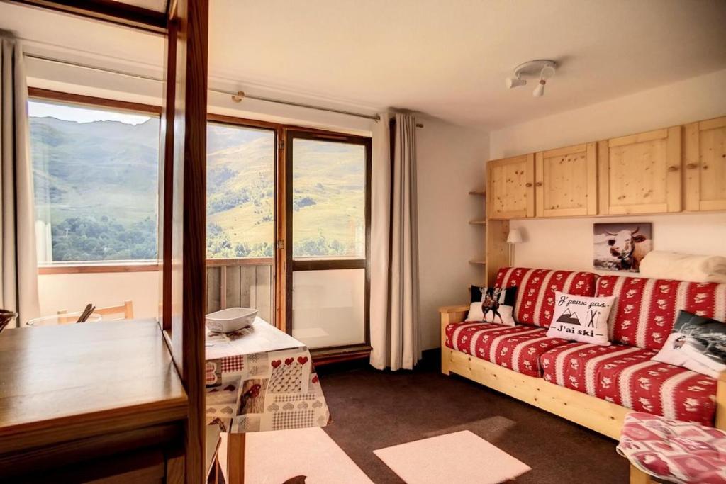 Cette chambre dispose d'un canapé et d'une grande fenêtre. dans l'établissement Résidence Sarvan - Appartement lumineux · Départ et retour skis aux pieds · Balcon MAE-2494, aux Menuires