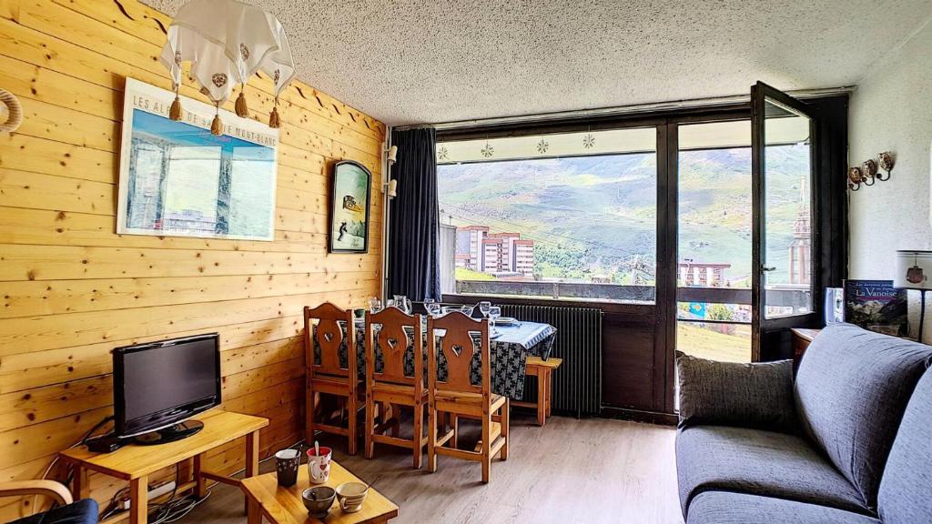 un salon avec une télévision et une table avec des chaises dans l'établissement Résidence Aravis - Appartement lumineux & confortable · Accès direct aux pistes · Balcon MAE-3034, aux Menuires