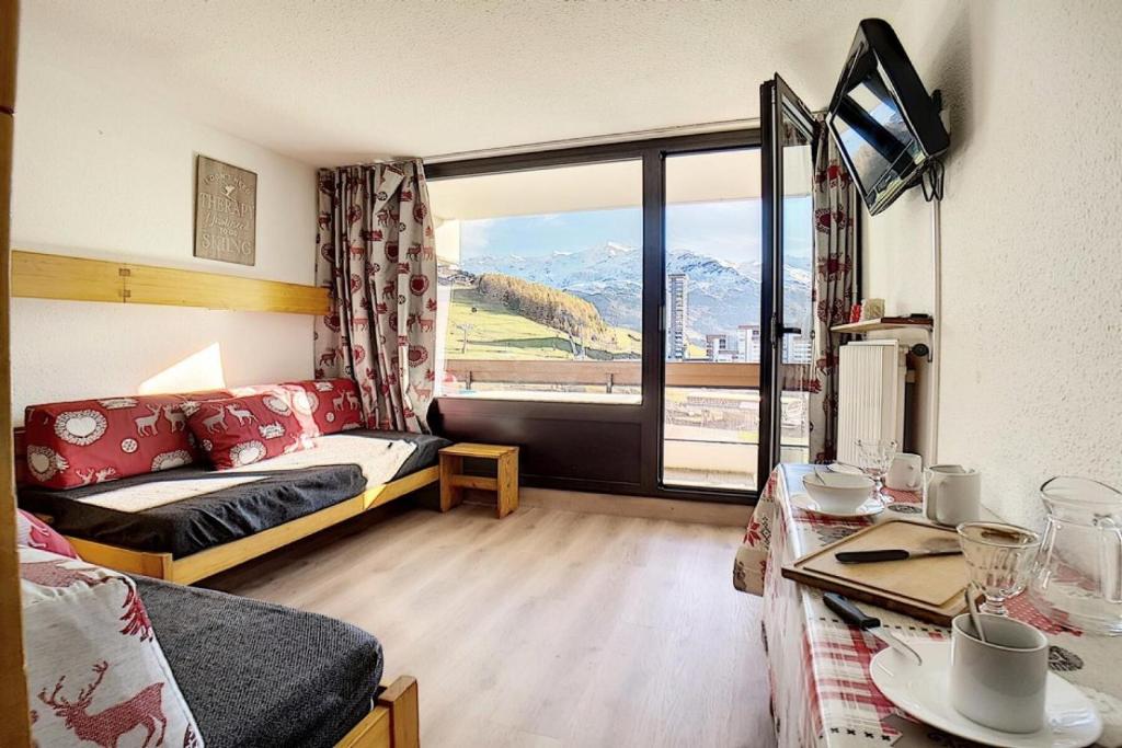 un salon avec un canapé et une grande fenêtre dans l'établissement Résidence Chaviere - Studio agréable · Ski au pieds · Balcon MAE-3154, aux Menuires