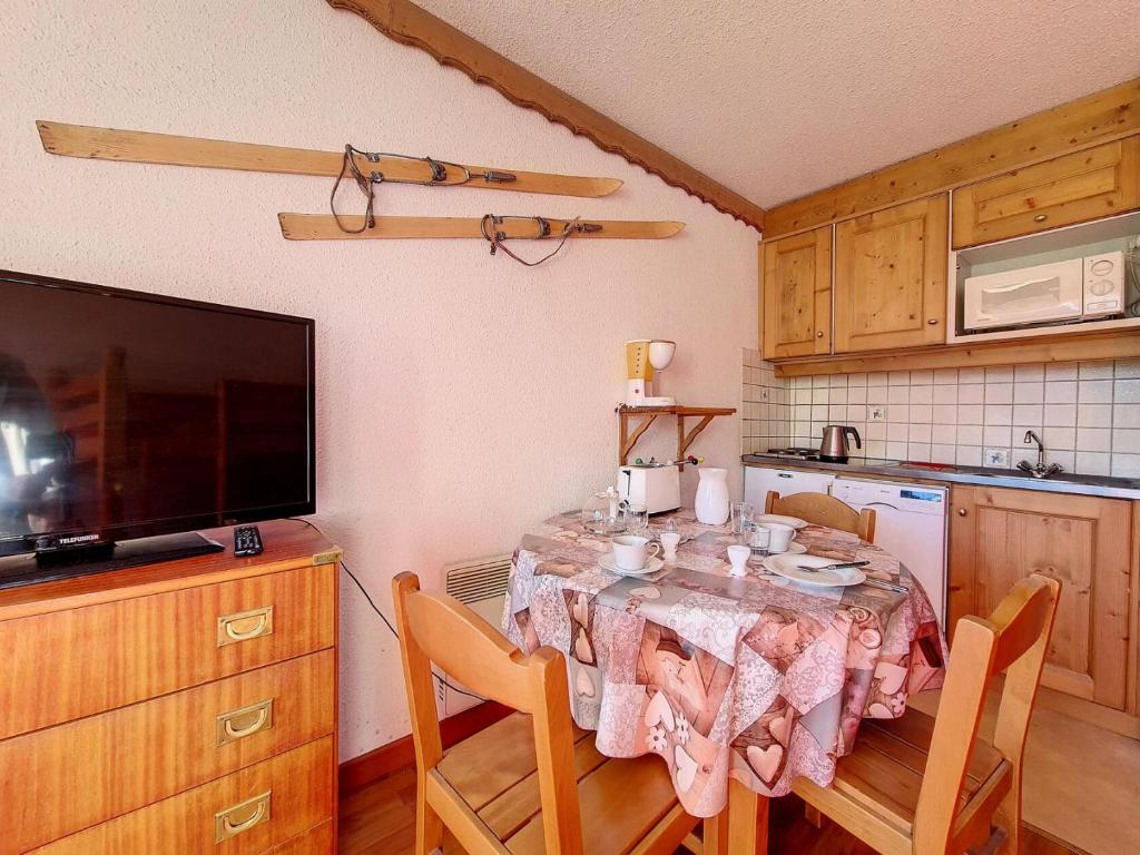 una cucina con un tavolo con sedie e una televisione di Résidence Grande Masse - Studio lumieux · Accès direct aux pistes · Balcon MAE-3324 a Les Menuires