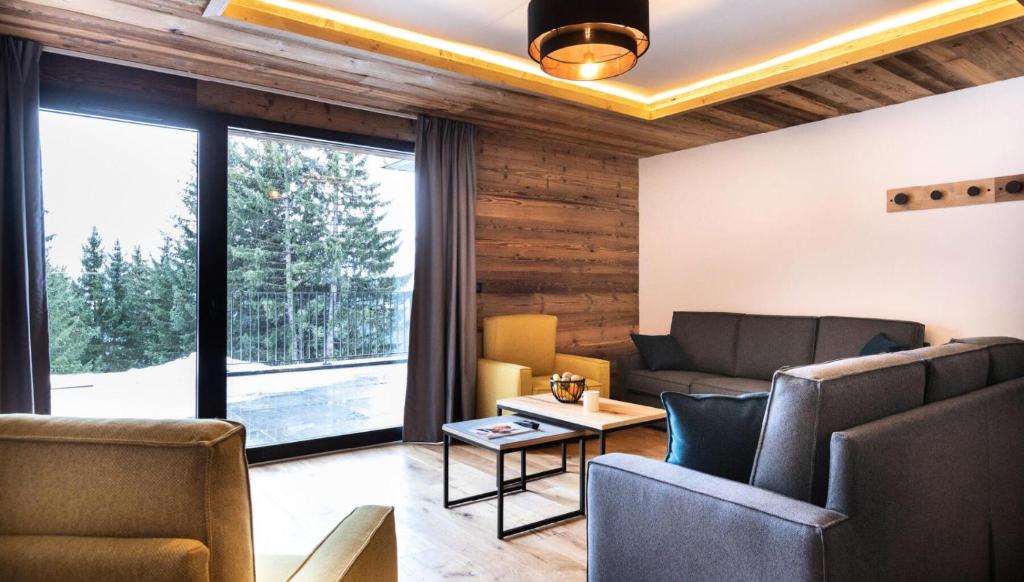 Elle comprend un salon meublé et une grande fenêtre. dans l'établissement Résidence OrÉe Du Bois - APPARTEMENT N°1 L'OREE DU BOIS MAE-9681, à Montvalezan