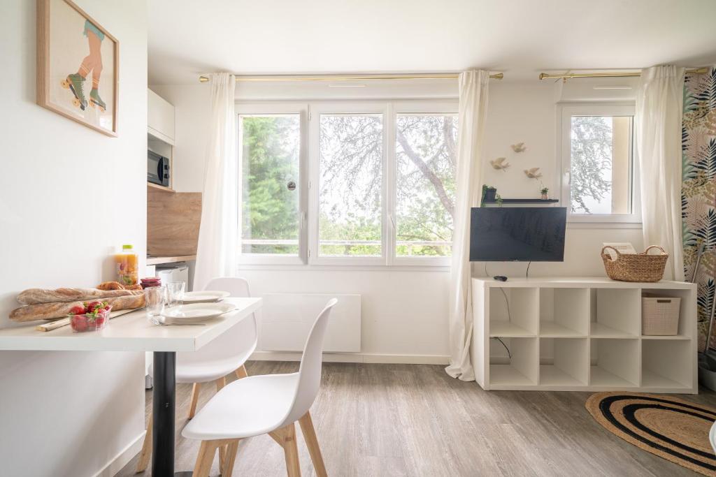 une salle à manger blanche avec une table et des chaises blanches dans l'établissement La Suite Le studio ANANAS vue sur jardin proche plages, à Saint-Nazaire