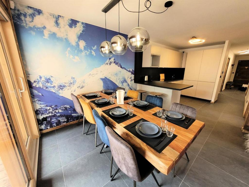 une salle à manger avec une table et une grande fresque murale. dans l'établissement Résidence Le Confidentiel - appartement neuf en plein centre, 8 personnes MAE-2441, aux Gets