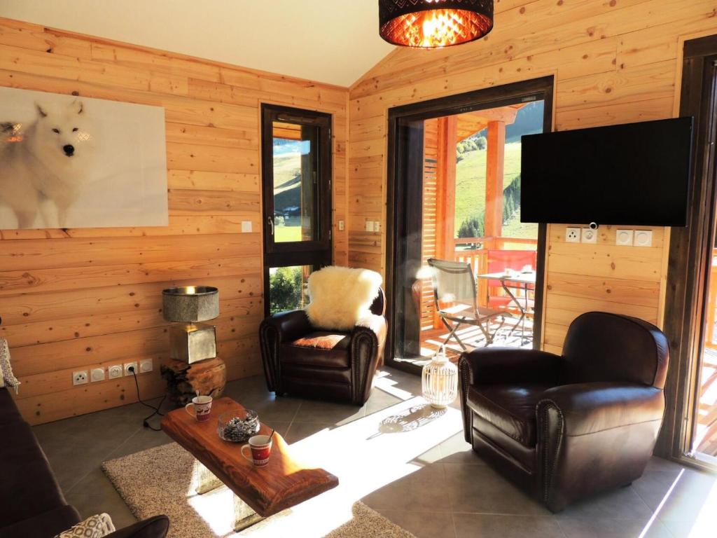 Il comprend un salon doté de fauteuils en cuir et d'une télévision à écran plat. dans l'établissement Les Chalets Carline - Appartement T3, vue dominante sur les pistes MAE-2561, aux Gets