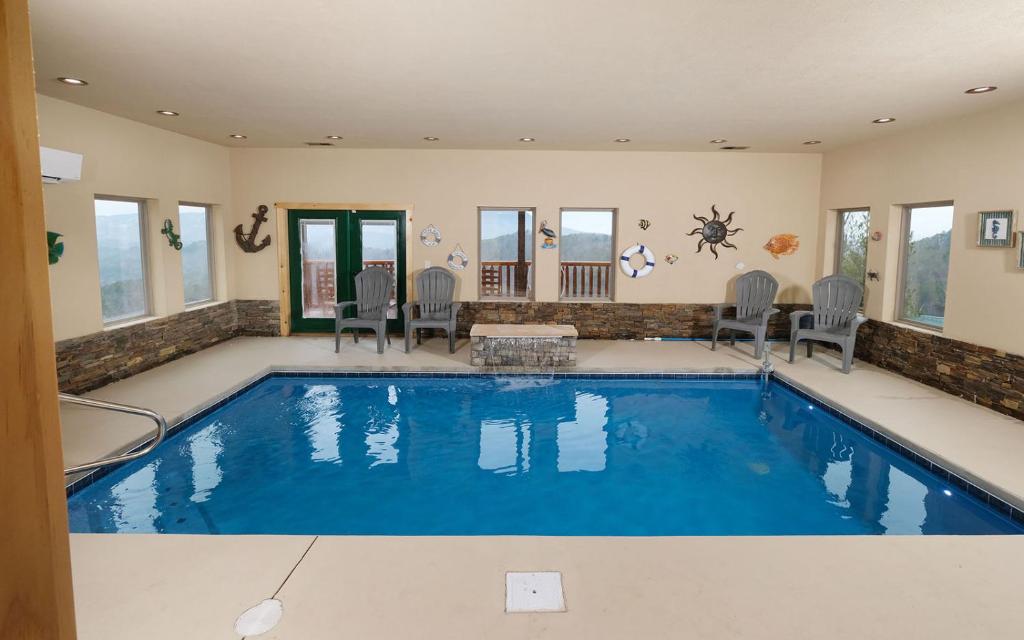 a large swimming pool with chairs and a table in a house at A Splash of Heaven in Pigeon Forge