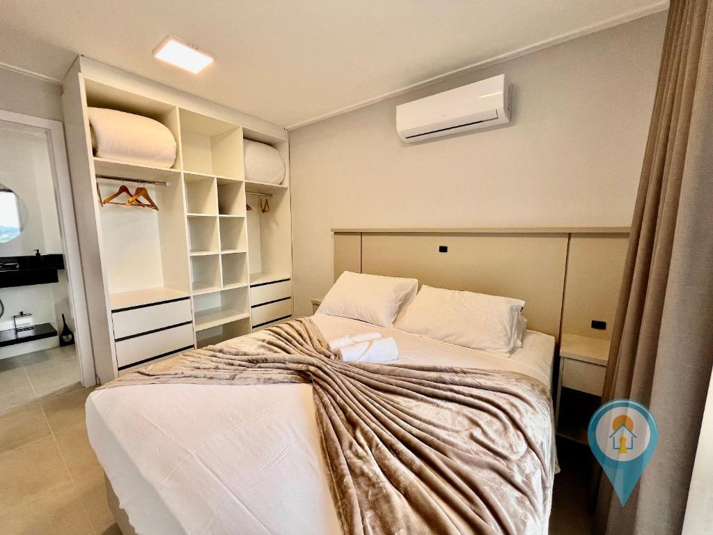 a bedroom with a large bed with white sheets at Aconchegante apartamento a 3 min. do Beto Carrero e Praia in São Lídio
