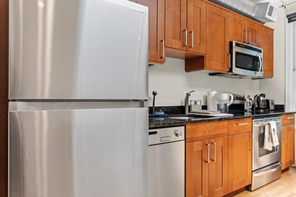a stainless steel refrigerator in a kitchen with wooden cabinets at Logan Circle Carriage House 1b-1b Central & Bright in Washington, D.C.
