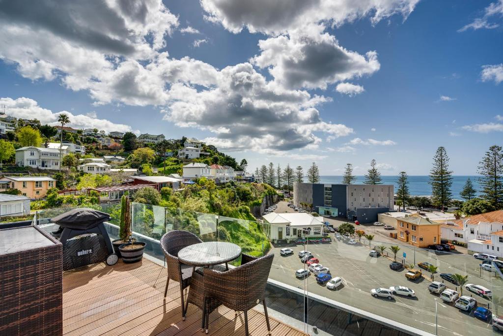 a balcony with a table and chairs and a city at Seabreeze Penthouse - Napier Holiday Apartment in Napier