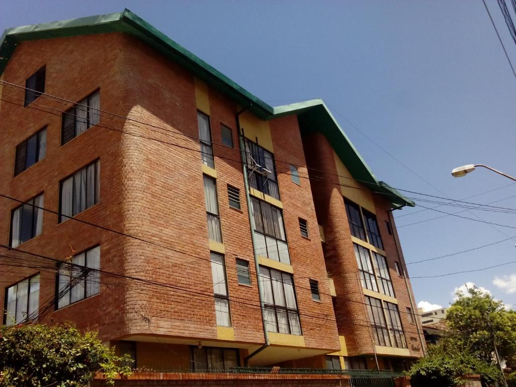 un bâtiment en briques rouges avec des fenêtres latérales dans l'établissement Apartamentos Sercan, à Cochabamba