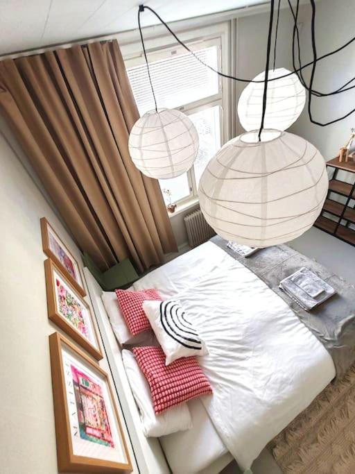 a bedroom with a bed with two lamps and pictures at Valoisa läpitalon kaksio in Porvoo