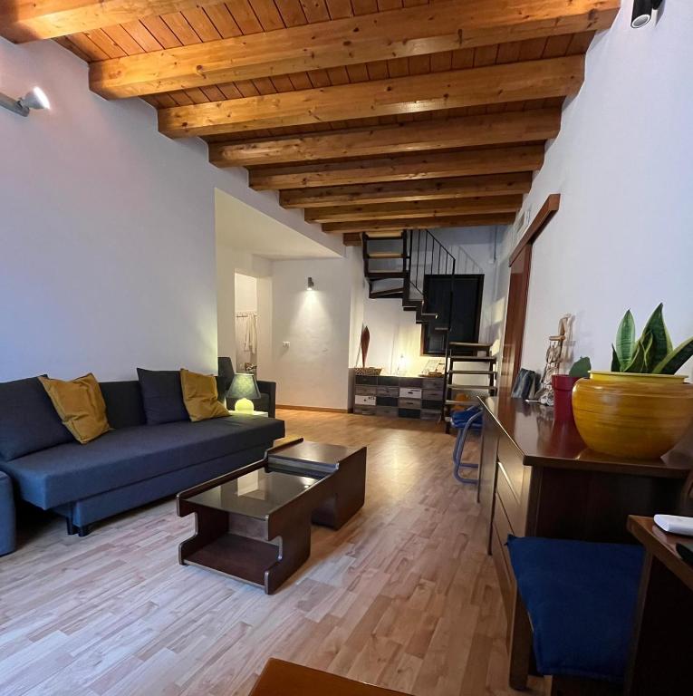 a living room with a blue couch and wooden ceilings at Fikus APT relax Castello Ursino in Catania