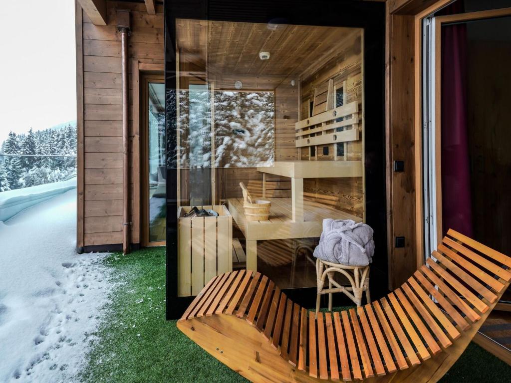 een houten huis met een bank en een tafel bij Kitzb heler Alpenlodge Top A6 with private panoramic sauna in Mittersill