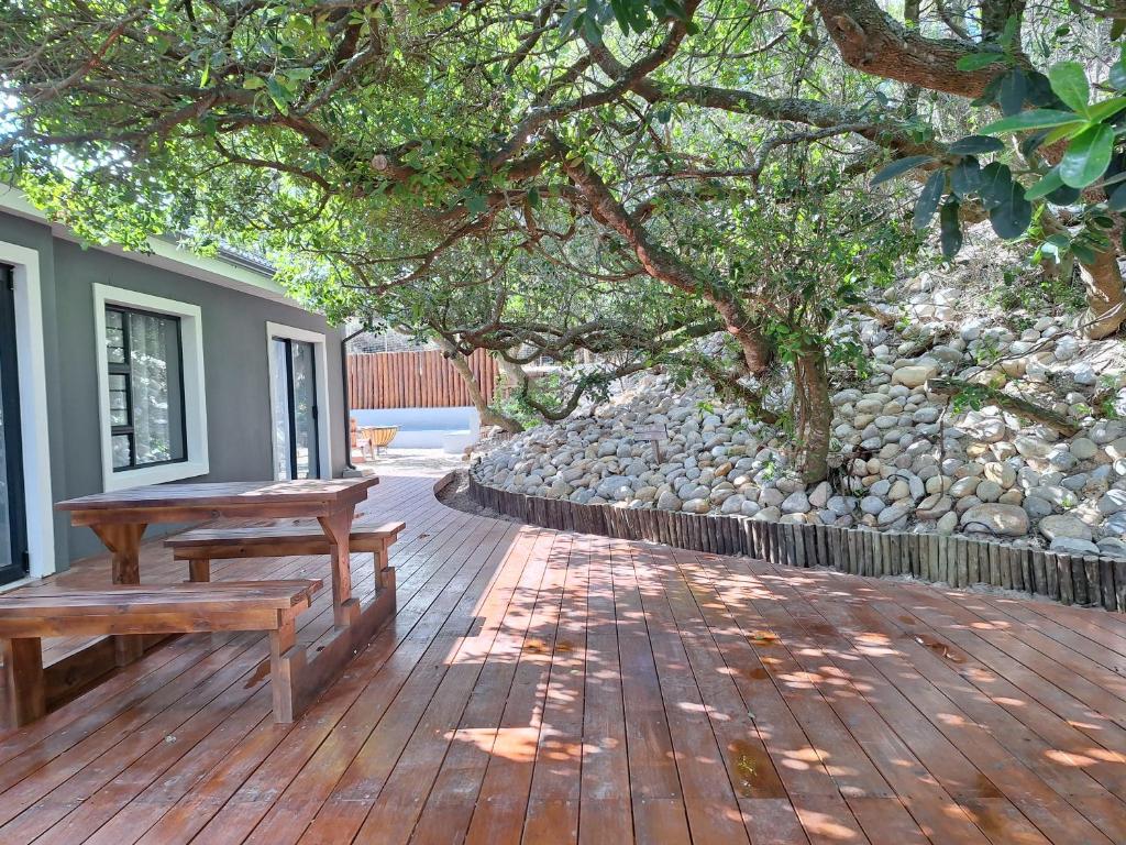 a wooden deck with two benches and a tree at The Beach House Paradise in Jeffreys Bay
