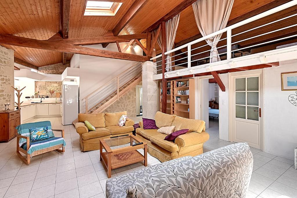 un salon avec des canapés et une mezzanine dans l'établissement Les Vents de Gironde - Maison en pierre piscine, à Chenac Saint Seurin D'uzet