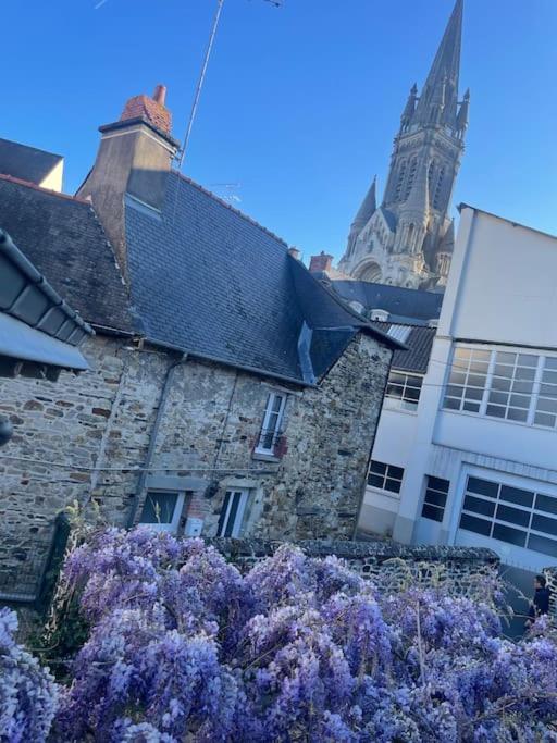 un bâtiment en pierre avec des fleurs violettes devant lui dans l'établissement Maison de ville- quartier calme, à Vitré
